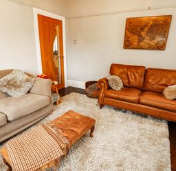 A living room with a sofa and footstool at 11 Bryn Goleu Avenue North Holyhead