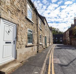 An outdoor street with stone buildings and a door at Blue Cottage in Malton