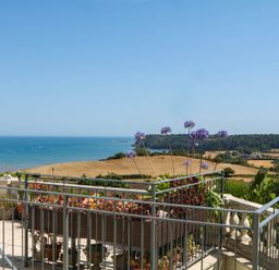 A balcony view of the sea and hills at Elberry Cove View in Paignton