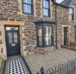 A front exterior view of a stone house with a gravel garden and bench in Rheidiol St Davids
