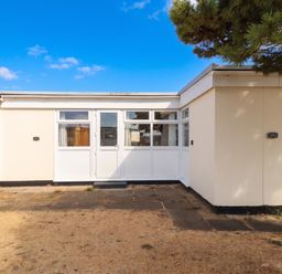 An outdoor view of a building with a patio and glass door at Chalet 242 Carmarthen Bay in Kidwelly