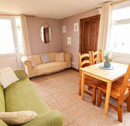 A living room with a green sofa and a dining table at Chalet 242 Carmarthen Bay in Kidwelly