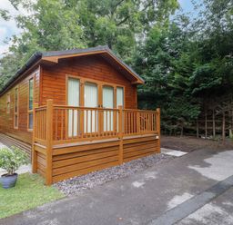 A wooden lodge with a porch and driveway at Fir Tree Lodge, White Cross bay on Windermere, Troutbeck Bridge