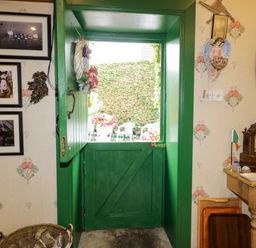 An entryway with a green door and photographs at Teresa's Cottage