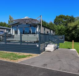 An outdoor area with a deck, sofa, and parasol at Lakewood Plot 9 in St. Osyth