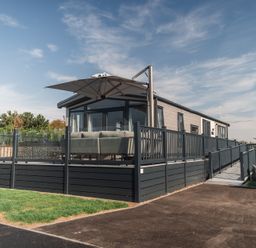 A house with a deck and umbrella at Lakewood Plot 9 St. Osyth