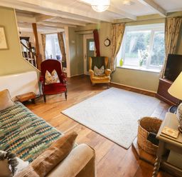 A living room with a sofa, armchair, and coffee table at Ty'r Wennol in Fishguard