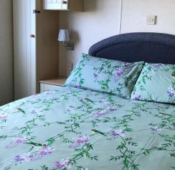 A bedroom with a bed and pillows at Beautifully Presented 2 Bedroom Static Caravan in Monreith near Whithorn