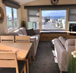 A living room with a sofa and dining table at Beautifully Presented 2 Bedroom Static Caravan in Monreith near Whithorn