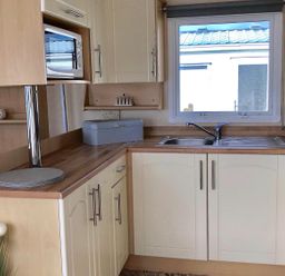 A kitchen with a sink and microwave at Beautifully Presented 2 Bedroom Static Caravan in Monreith near Whithorn