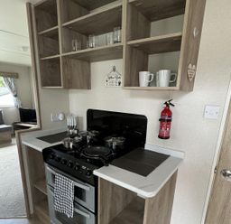 A kitchen with a stove and shelves at West Lawn 47 Haggerston Castle Paddock Views Haggerston