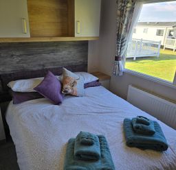 A bedroom with a double bed and towels at 3 Bed-Sleeps 8-Free Parking-5 Min to Beach Embo near Dornoch