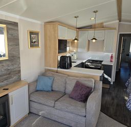 A living room with a sofa and kitchen area at 3 Bed-Sleeps 8-Free Parking-5 Min to Beach in Embo near Dornoch