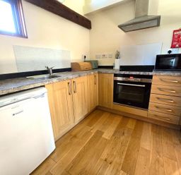 A kitchen with a sink, cabinets, microwave, and oven at Barn Conversion Sleeps 2 with Parking in Diss