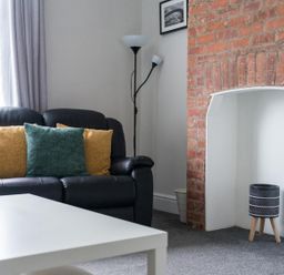 A living room with a sofa and cushions at East House-Sleeps 5-Pet friendly-Garden-Parking in Stakeford