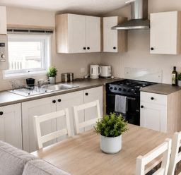 A kitchen with modern appliances and a dining table at 3 Bedroom Cabin Sleeps 6 - Shared Pool & Shared Hot Tub, Flamingo Land Resort near Malton