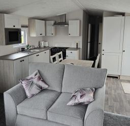 A kitchen with a couch, table, and appliances at 3 Bedroom Cabin Sleeps 6 - Shared Pool & Shared Hot Tub, Flamingo Land Resort near Malton