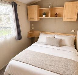 A bedroom with a bed and shelves at Seaside Tranquility Retreat in Clacton