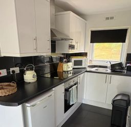 A kitchen with cabinets and appliances at Pet Friendly 2-Bed Lodge, Sleeps 5, Pool & Parking, Caernarfon