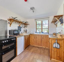 A kitchen with stove, refrigerator, and sink at 3-Bed Barn Eco-Lodge on the Tarka trail East Yarde near Great Torrington