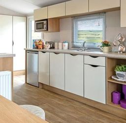 A kitchen with cabinets and appliances at Seafront Caravan - Golden Sands - 6 Berth by Your Away Stays Kinmel Bay