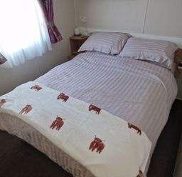 A bed with a blanket in a bedroom at Seafront Caravan - Golden Sands - 6 Berth by Your Away Stays in Kinmel Bay