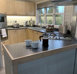 A kitchen with coffee cups and a coffee maker at Holly Blue - Cosy wooden lodge, Kippford
