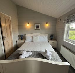 A bedroom with a bed and bedside tables at Holly Blue - Cosy wooden lodge, Kippford