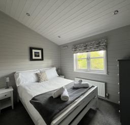 A bedroom with a bed and nightstand at Holly Blue - Cosy wooden lodge, Kippford