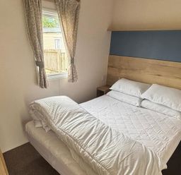 A bedroom with a bed and window at Caravan Sleeps 5 - Decking, Parking, Pet Friendly, Blackpool
