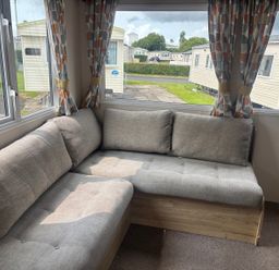 A living room with a sofa near a window at Caravan Sleeps 5 - Decking, Parking, Pet Friendly in Blackpool