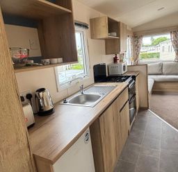 A kitchen with a sink, cooker, and microwave at Caravan Sleeps 5 - Decking, Parking, Pet Friendly in Blackpool