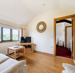 A living room with a sofa and a table at The Shippon, Breathtaking Views, Private Hot Tub, Winkleigh