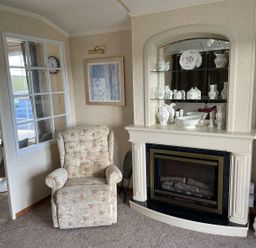 A living room with an armchair and fireplace at Chalet Sleeps 4 Near Cymyran Beach Caergeiliog