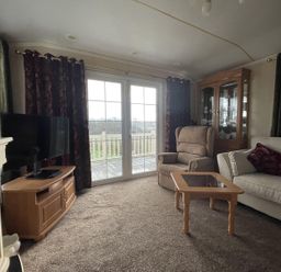 A living room with a television and sliding door at Chalet Sleeps 4 Near Cymyran Beach in Caergeiliog