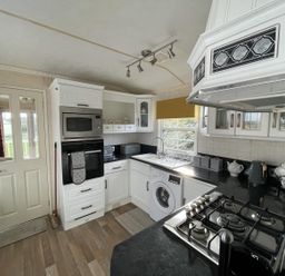 A kitchen with appliances and cabinetry at Chalet Sleeps 4 Near Cymyran Beach Caergeiliog