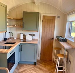 A kitchen with green cabinets and wooden countertops at Peaceful Shepherd Hut near Clovelly