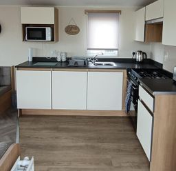 A kitchen with appliances and seating at Golden Sands 3-Bed Caravan, Parking and Pet Friendly in Towyn