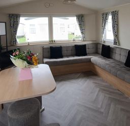 A living room with a corner sofa and a table at Golden Sands 3-Bed Caravan, Parking and Pet Friendly in Towyn
