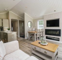 A living room with a sofa, dining area and wall-mounted television at 19 Pony Meadow near White Cross Bay