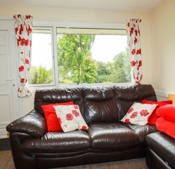 A living room with a sofa and window view at Villa 12 near Camelford