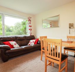 A living room with a sofa and dining table at Villa 12 near Camelford