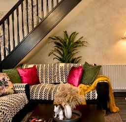 A living room with a sofa and staircase at Muddy Boots – La Petite Mews in Kirby Stephen
