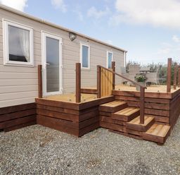 An exterior view of a mobile home with a wooden deck near Little Haven