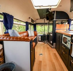 A kitchen with a sofa and kitchen appliances at Honey Bee Bus Menheniot