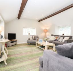 A living room with a sofa and coffee table at Peewit Barn in Moreton-in-Marsh