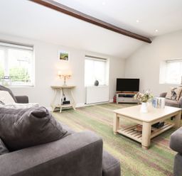 A living room with a sofa and coffee table at Peewit Barn in Moreton-in-Marsh