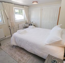 A bedroom with a double bed and a chair at Hafan y Tyddyn