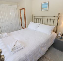 A bedroom with a bed, side table, lamp, and mirror at Hafan y Tyddyn