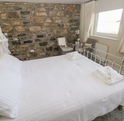A bedroom with a bed and chair at Hafan y Tyddyn